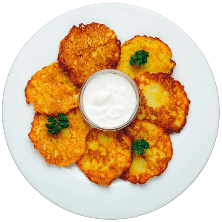 Plate of crispy potato pancakes with sour cream and parsley garnish